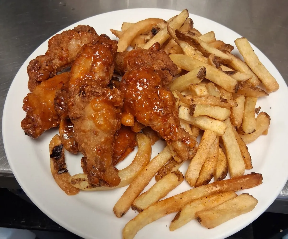 Chicken wings in a glossy sauce with fries